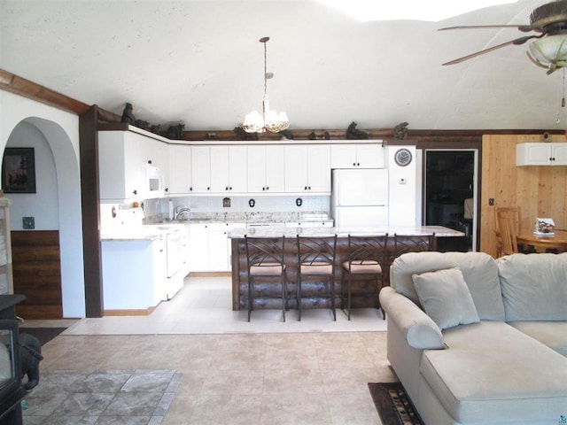 living room with wood walls, ceiling fan with notable chandelier, arched walkways, and light tile patterned floors
