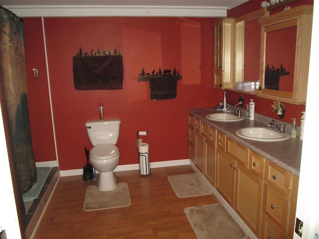 full bath with toilet, wood finished floors, and a sink