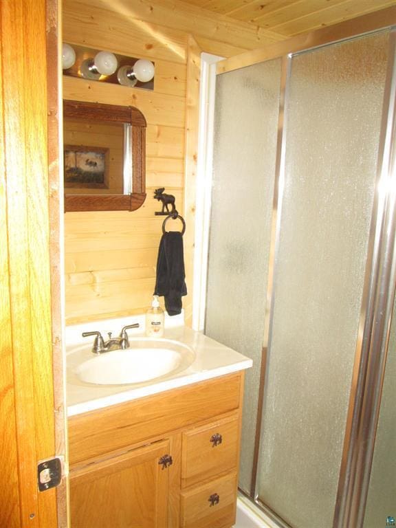 bathroom featuring a stall shower, vanity, wooden walls, and wooden ceiling