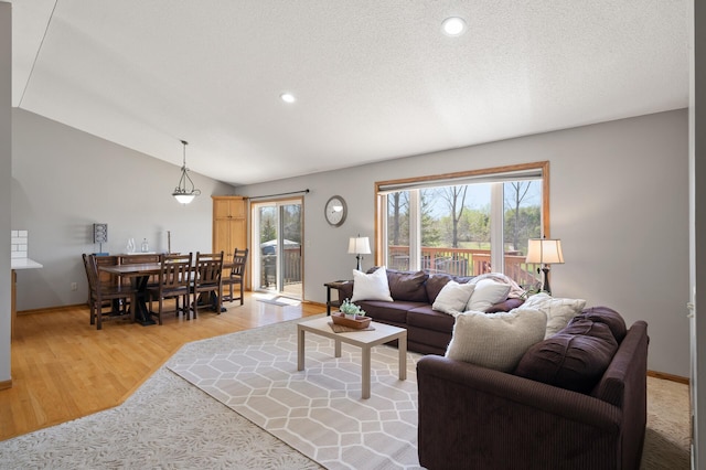 living room featuring light wood finished floors, lofted ceiling, baseboards, and recessed lighting