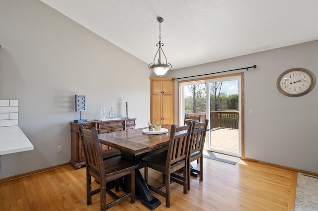 dining area featuring light wood finished floors, vaulted ceiling, and baseboards