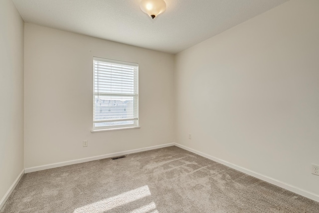 carpeted spare room with baseboards and visible vents