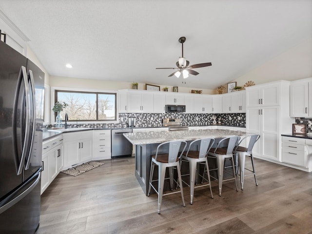 10823 Big Chip Rd NW, Brandon Twp, MN 56315 - kitchen featuring appliances with stainless steel finishes, lofted ceiling, decorative backsplash, ceiling fan, and a kitchen bar