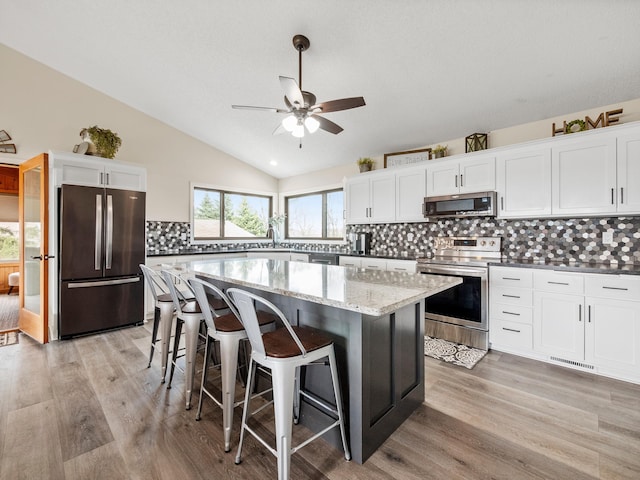 10823 Big Chip Rd NW, Brandon Twp, MN 56315 - kitchen with appliances with stainless steel finishes, decorative backsplash, vaulted ceiling, a ceiling fan, and a kitchen island