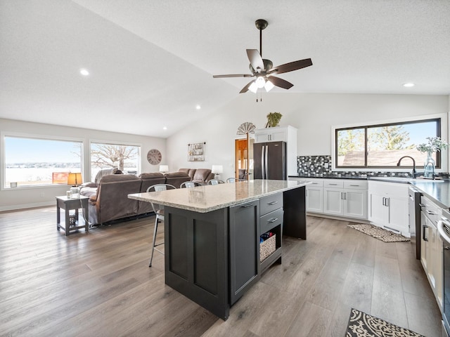 10823 Big Chip Rd NW, Brandon Twp, MN 56315 - kitchen with freestanding refrigerator, vaulted ceiling, white cabinets, a center island, and light wood-type flooring