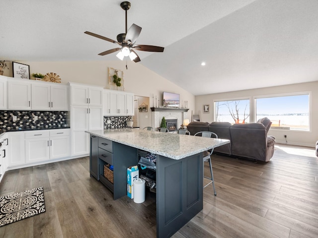 10823 Big Chip Rd NW, Brandon Twp, MN 56315 - kitchen with white cabinetry, open floor plan, wood finished floors, a breakfast bar area, and vaulted ceiling