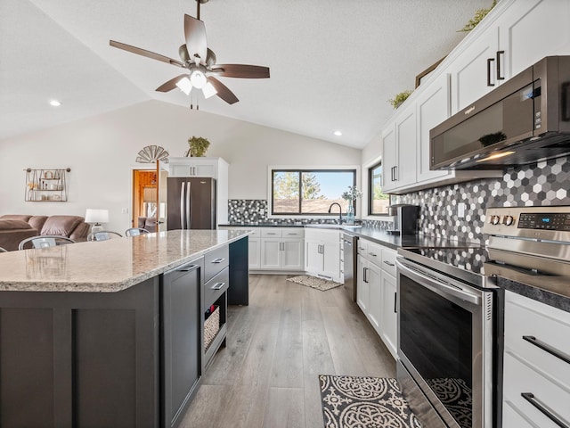 10823 Big Chip Rd NW, Brandon Twp, MN 56315 - kitchen with stainless steel appliances, lofted ceiling, white cabinets, decorative backsplash, and ceiling fan