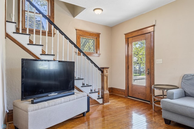 foyer featuring wood-type flooring, stairway, and baseboards