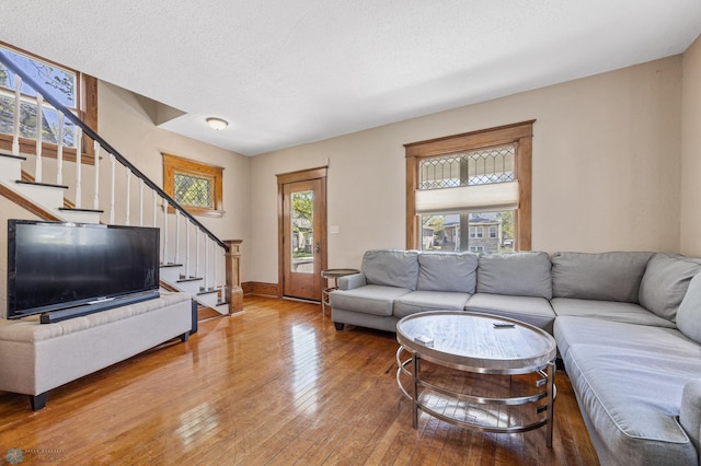 living area with stairs, light wood-type flooring, and baseboards