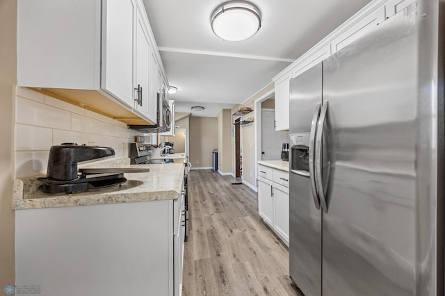 kitchen with stainless steel appliances, tasteful backsplash, white cabinets, and light wood-style flooring