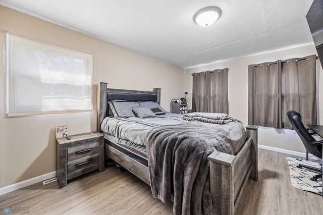 bedroom with light wood-style flooring and baseboards