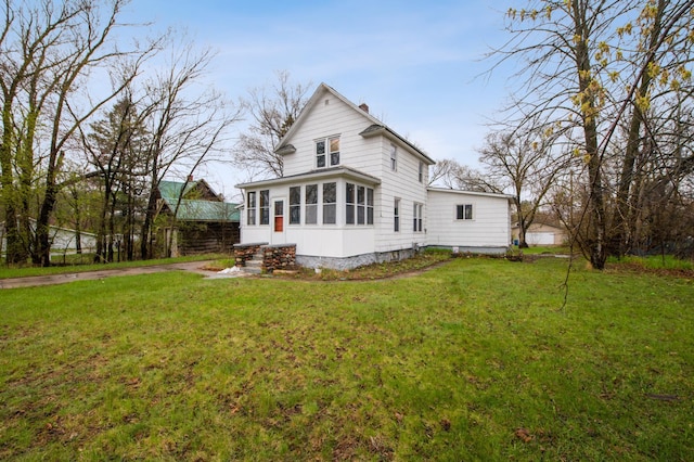 rear view of house featuring a sunroom and a yard