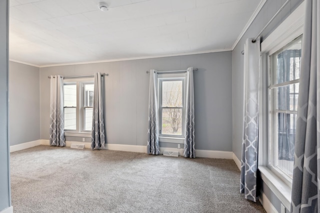 carpeted empty room featuring a healthy amount of sunlight, crown molding, and visible vents