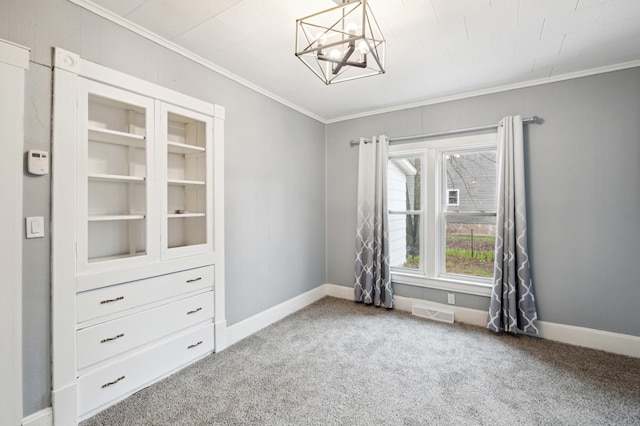 carpeted spare room featuring baseboards, visible vents, an inviting chandelier, and crown molding