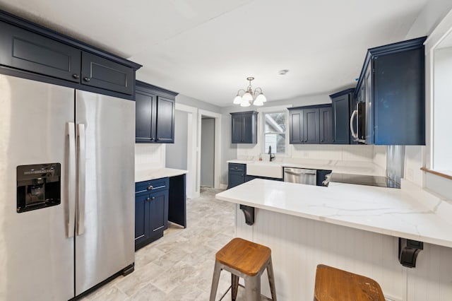 kitchen with a sink, a peninsula, a kitchen bar, a notable chandelier, and appliances with stainless steel finishes