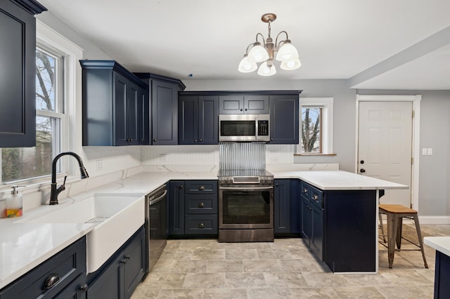 kitchen with a peninsula, a breakfast bar, a sink, appliances with stainless steel finishes, and a chandelier