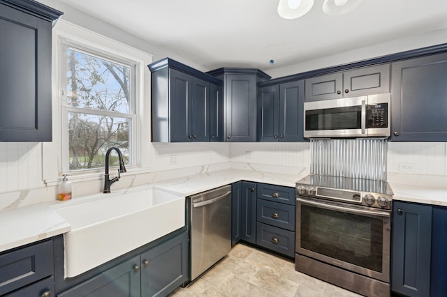 kitchen with stone finish floor, light stone counters, appliances with stainless steel finishes, and a sink