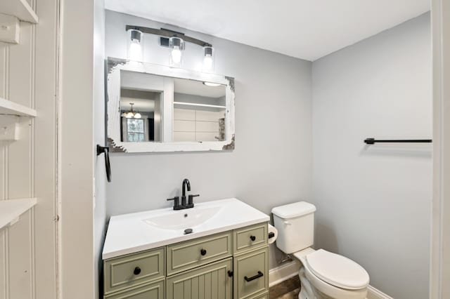 bathroom with toilet, baseboards, and vanity