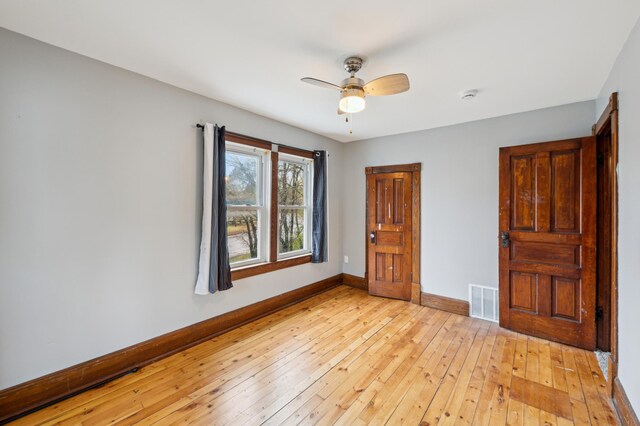 spare room featuring a ceiling fan, visible vents, baseboards, and light wood-style flooring