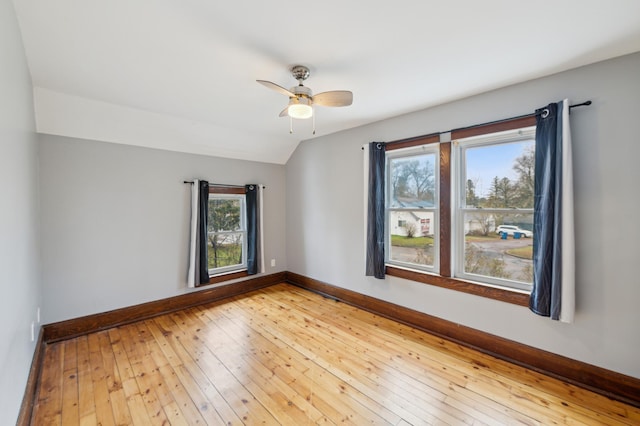 unfurnished room featuring vaulted ceiling, hardwood / wood-style flooring, baseboards, and a ceiling fan