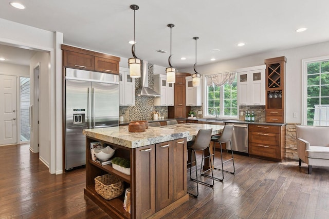8622 French Curv, Eden Prairie, MN 55347 - kitchen featuring appliances with stainless steel finishes, wall chimney range hood, dark wood-type flooring, tasteful backsplash, and glass insert cabinets