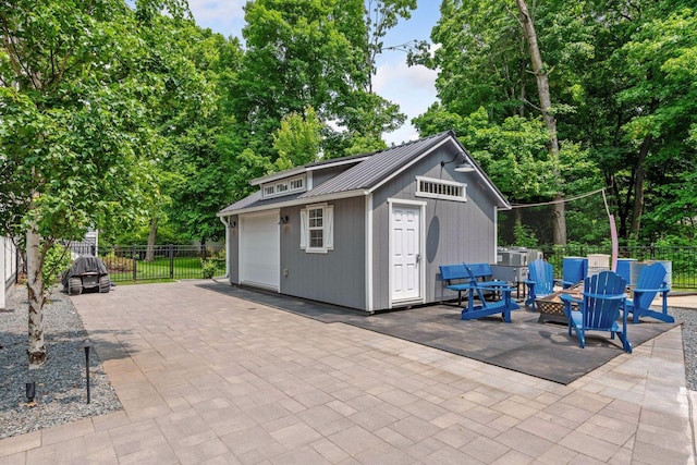 8622 French Curv, Eden Prairie, MN 55347 - view of patio / terrace featuring an outdoor structure, a detached garage, a fire pit, and view of wooded area