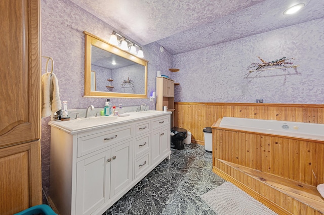 1320 18th St SE, Owatonna, MN 55060 - full bathroom featuring double vanity, marble finish flooring, a wainscoted wall, toilet, and a bathtub