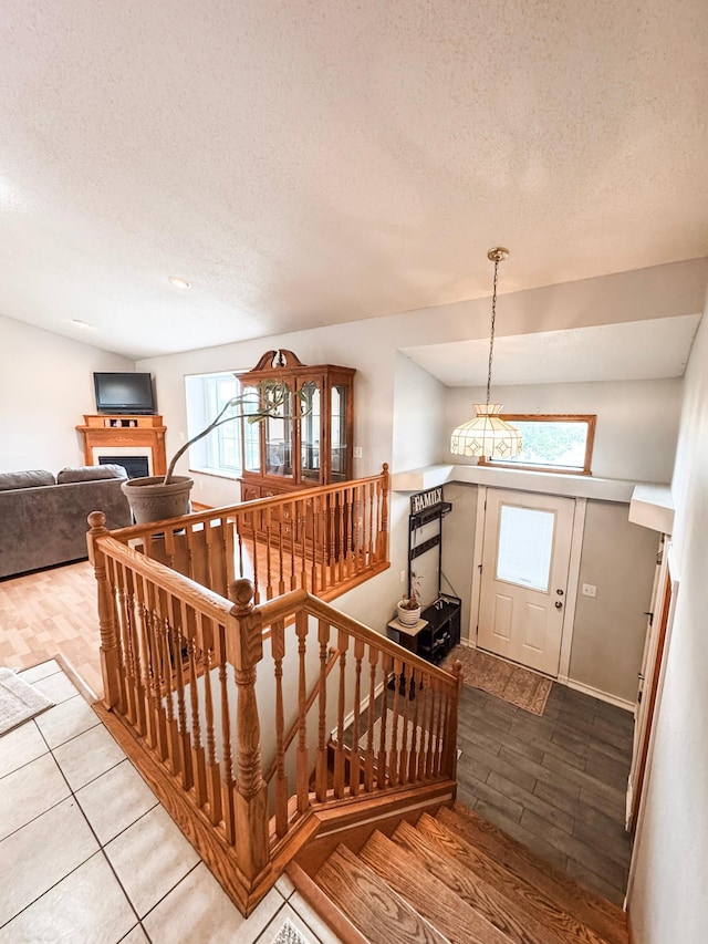 1320 18th St SE, Owatonna, MN 55060 - stairs with a textured ceiling, a chandelier, wood finished floors, and a fireplace