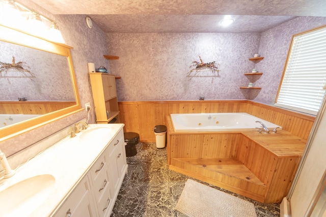 1320 18th St SE, Owatonna, MN 55060 - full bathroom featuring a jetted tub, wooden walls, a wainscoted wall, double vanity, and marble finish floors