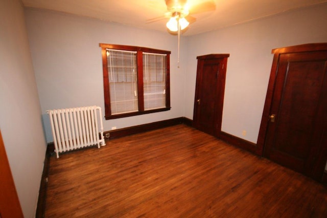 unfurnished bedroom featuring radiator, wood finished floors, baseboards, and ceiling fan