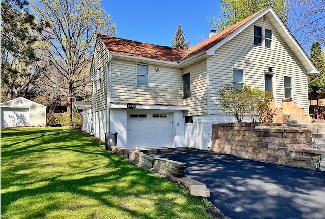 view of front of home with a front yard, driveway, a chimney, and a garage