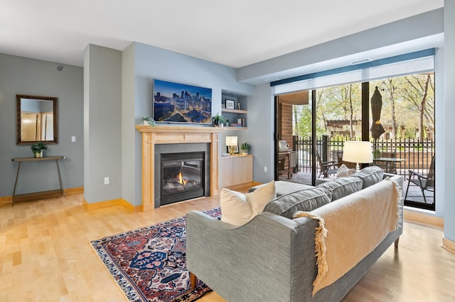 living room with wood finished floors, a glass covered fireplace, and baseboards