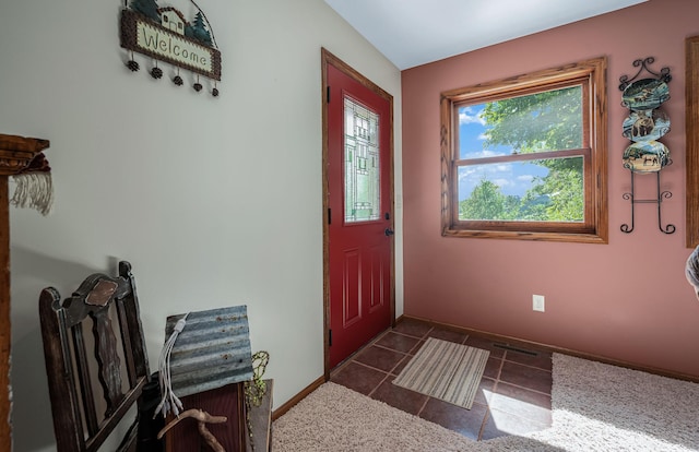 entrance foyer with dark tile patterned floors and baseboards