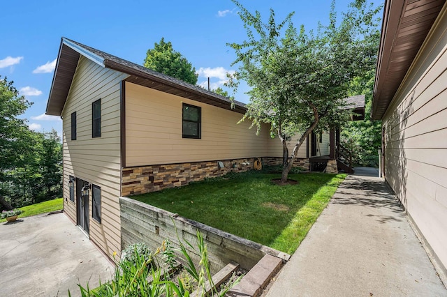 view of home's exterior featuring a patio area, an attached garage, and a lawn