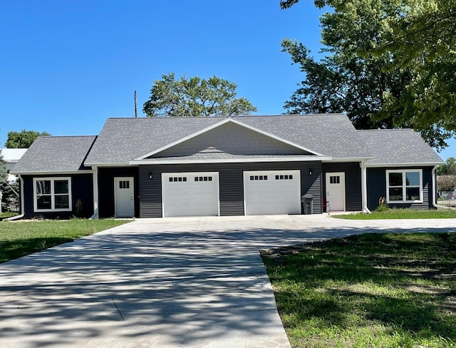 view of front of house with concrete driveway, a front lawn, a shingled roof, and an attached garage