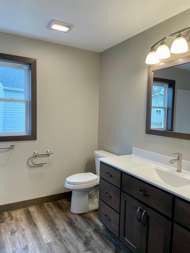 bathroom featuring toilet, baseboards, wood finished floors, and vanity