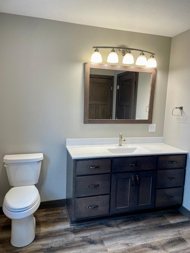 bathroom with baseboards, vanity, toilet, and wood finished floors