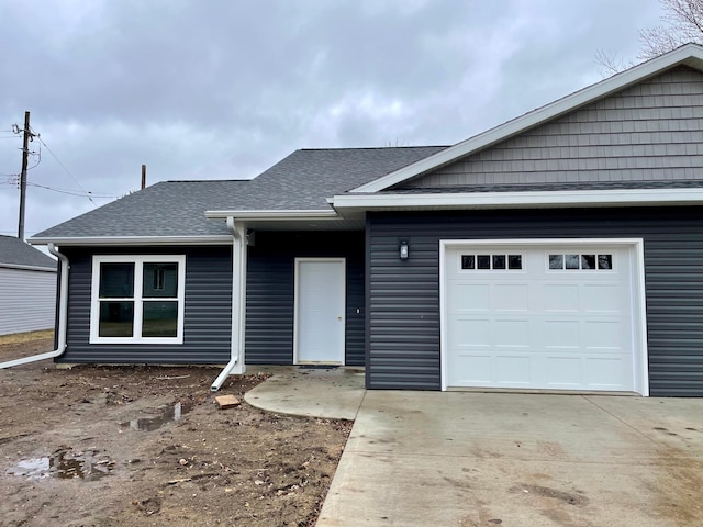 single story home with concrete driveway, roof with shingles, and an attached garage