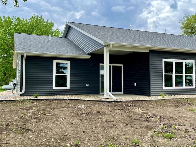 back of property featuring a shingled roof and a patio area