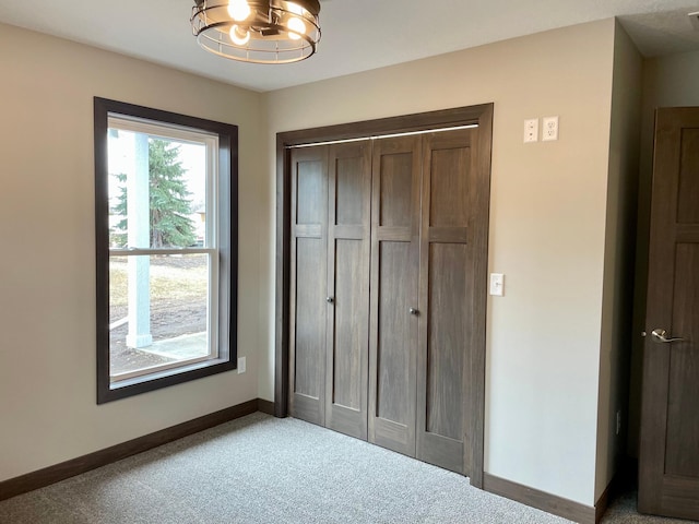 unfurnished bedroom with carpet flooring, a closet, a chandelier, and baseboards