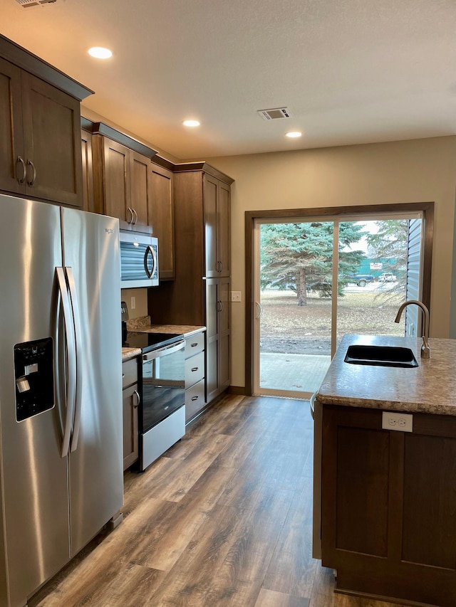 kitchen with appliances with stainless steel finishes, plenty of natural light, wood finished floors, and a sink