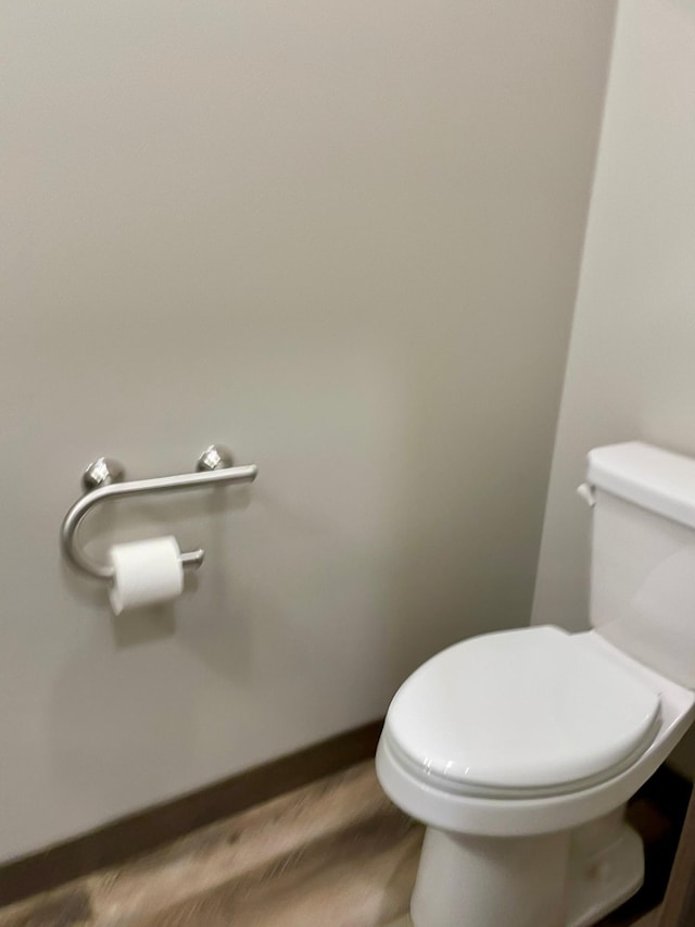 bathroom with toilet, baseboards, and wood finished floors