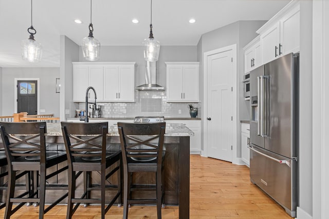 4152 Hummingbird Ct N, Lake Elmo, MN 55042 - kitchen featuring high end fridge, backsplash, white cabinetry, light wood-style floors, and wall chimney range hood