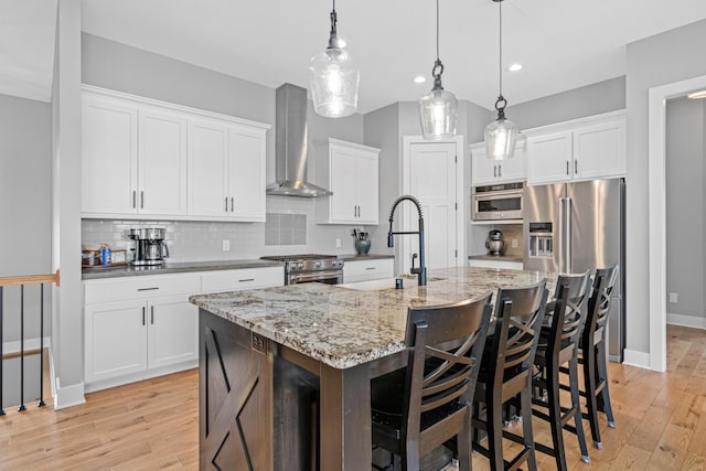 4152 Hummingbird Ct N, Lake Elmo, MN 55042 - kitchen featuring wall chimney range hood, stainless steel appliances, a sink, backsplash, and light wood finished floors