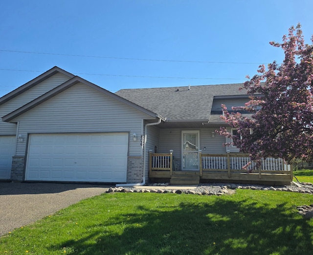 view of front of property with a garage, roof with shingles, driveway, a front lawn, and brick siding