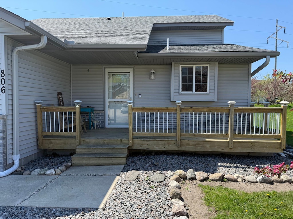 rear view of house with roof with shingles and a deck