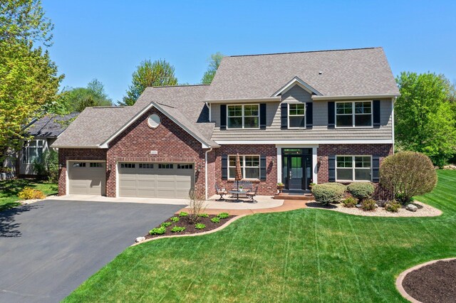 view of front of home featuring brick siding, a garage, driveway, and a front lawn