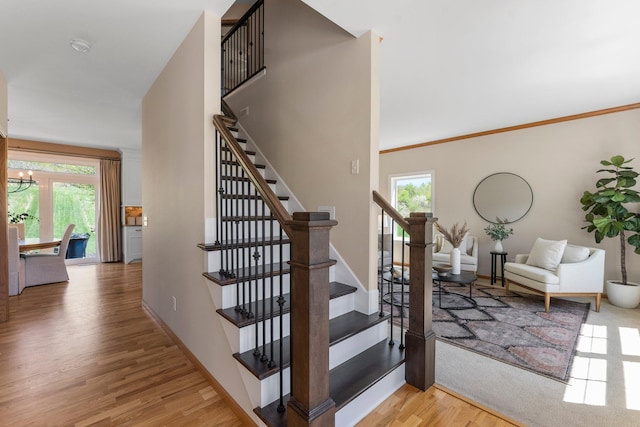 staircase featuring wood finished floors, baseboards, and a chandelier
