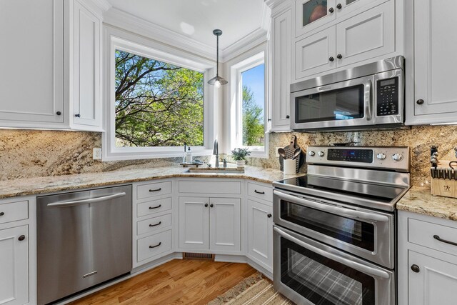 kitchen with stainless steel appliances, a sink, white cabinetry, and ornamental molding