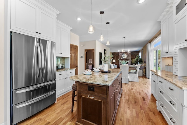 kitchen featuring freestanding refrigerator, white cabinets, light wood-type flooring, a kitchen island, and recessed lighting